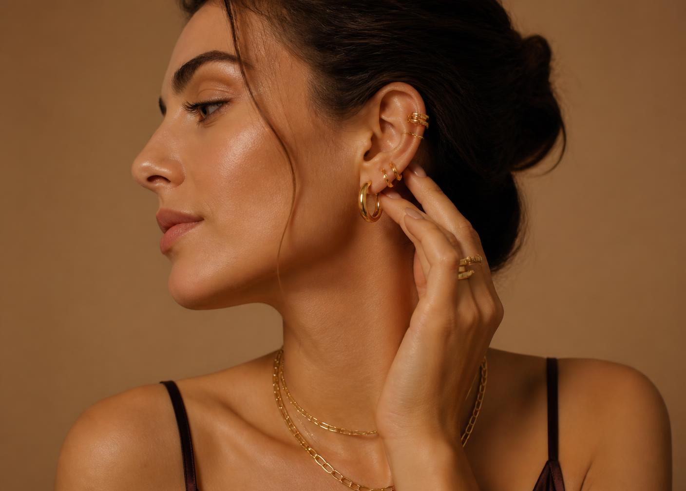 Modelo con pendientes, anillos y collares dorados de Be You Brand