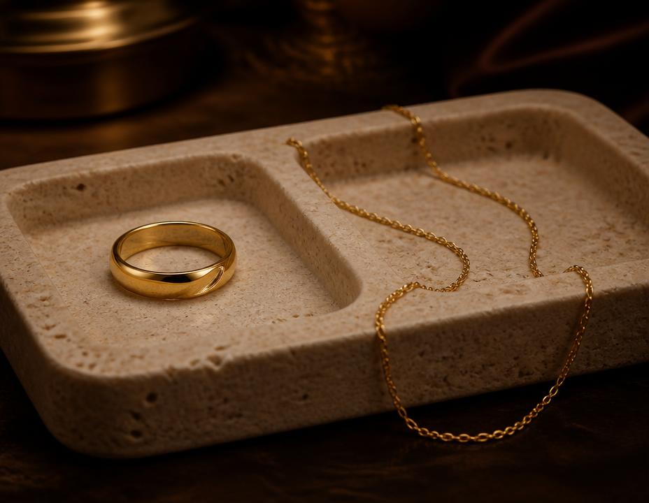 Anillo y collar dorados sobre bandeja de piedra